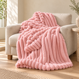 Blush Reverie bubble faux-fur throw on an oatmeal linen armchair. AI-styled scene based on supplier photography; colour and texture pending sample verification.